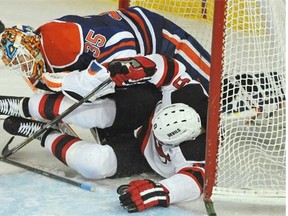 New Jersey Devils Dainius Zubrus, bottom, crashes into Edmonton Oilers goalie Viktor Fasth during third period NHL action at Rexall Place in Edmonton on Friday, Nov. 22, 2014.