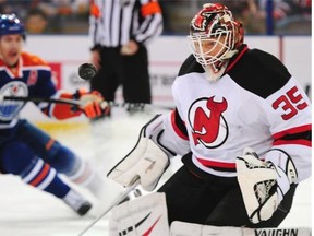 New Jersey Devils goalie Cory Schneider makes a save as Edmonton Oilers forward Taylor Hall approaches the net during NHL action at Rexall Place in Edmonton on Nov. 21, 2014.