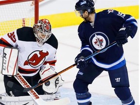 New Jersey Devils goalie Cory Schneider stops the deflection by THE Winnipeg Jets’ Matt Halischuk during first period NHL action in Winnipeg on Nov. 18, 2014.