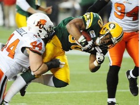 John White (30)of the Edmonton Eskimos, is tackled by Adam Bighill (44) of the B.C. Lions at Commonwealth Stadium in Edmonton.