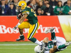 John White, left, of the Edmonton Eskimos runs with the ball past Chad Kilgore of the Saskatchewan Roughriders during a CFL game at Commonwealth Stadium in Edmonton on Friday, Sept. 26, 2014.