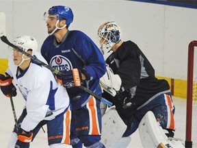 Jordan Oesterie (left), and Mitch Moroz obscure the vision of Edmonton Oilers prospect goalie Laurent Borssoit during the opening day of training camp Friday at Rexall Place.