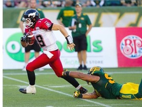 Bo Levi Mitchell #19 of the Calgary Stampeders slips past Eddie Steele #97 of the Edmonton Eskimos during second half action at Commonwealth Stadium on Saturday Sept. 6, 2014.