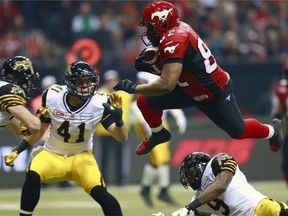 Nik Lewis #82 of the Calgary Stampeders leaps over Brandon Stewart #9 and into Erik Harris #41 and Craig Butler #28 of the Hamilton Tiger-Cats during the 102nd Grey Cup Championship Game at BC Place Nov. 30, 2014 in Vancouver.