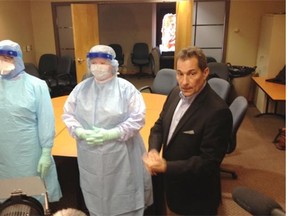 Dr. Mark Jofee, the senior medical director for infection  prevention and control for Alberta Health Services, poses Tuesday with two health care workers wearing gear to protect them from Ebola.