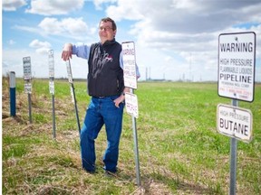 Neil Shelly, executive director of Alberta’s Industrial Heartland Association, poses with signs for several ethane, propane and butane gas lines northeast of Fort Saskatchewan in May 2013. Pipelines criss-cross the area, feeding the refineries and petrochemical plants northeast of Edmonton.