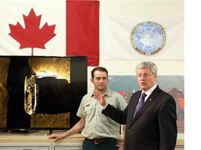 Canada's Prime Minister, Stephen Harper (R) and Ryan Harris, Senior Underwater Archeologist for Parks Canada stand in front of an image of one of the ships belonging to the ill-fated Franklin Expedition which was lost in 1846, September 9, 2014.