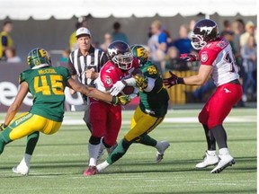 An official in the background watches as Jock Sanders of the Calgary Stampeders tries to squeeze between Dexter McCoil (45) and Eric Samuels of the Edmonton Eskimos during Saturday’s Canadian Football League game at Commonwealth Stadium.