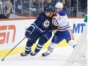 The Oilers’ Andrew Ference and the Jets’ Jacob Trouba battle for a loose puck during the Jets' overtime win in Winnipeg Wednesday, Dec. 3, 2014.