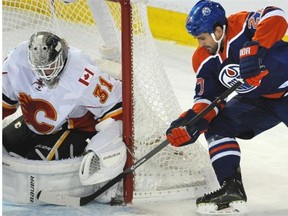 Oilers’ Boyd Gordon, left, tries to jam the puck past Calgary Flames goalie Karri Ramo during Edmonton’s NHL season-opening game at Rexall Place in Edmonton, October 9, 2014.