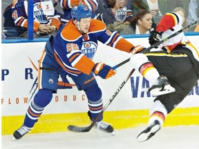 The Oilers’ Nikita Nikitin checks a Calgary Flames player during the second period at Rexall Place on Thursday, Oct. 9, 2014.