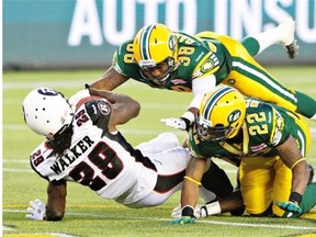 Ottawa RedBlacks running back Chevon Walker gets tackled by Eric Samuels (38) and Joe Burnett (22) of the Edmonton Eskimos in a Canadian Football League game at Commonwealth Stadium on July 11, 2014. Both Samuels and Burnett are injured and will miss Friday’s return match in Ottawa.