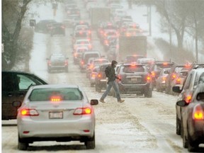 A pedestrian crosses the street on River Valley Road while traffic was at a stand-still due to slippery road conditions and heavy snowfall in Edmonton on November 27, 2014.