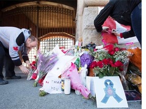 A man places flowers at a makeshift memorial to Nathan Cirillo that has been growing outside of The Lieutenant-Colonel John Weir Foote Armoury in Hamilton, Ontario on Thursday, Oct. 23, 2014. Cirillo, who was shot and killed in Ottawa on Wednesday, was a reservist who was only on a short-term posting at the National War Memorial. THE CANADIAN PRESS/Peter Power
