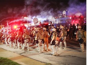 Police advance through a cloud of tear gas toward demonstrators protesting the killing of teenager Michael Brown on Aug. 17, 2014 in Ferguson, Mo.