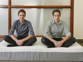 Sam Prochazka (left) and his brother Andy Prochazka (right) sit on one of their mattresses outside their office in downtown Edmonton on Nov. 24, 2014. Their business, Novosbed, is an online foam mattress retailer.