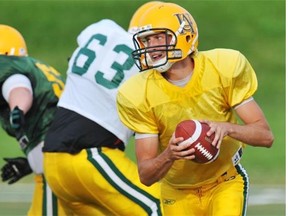 Quarterback Curtis Dell, right, scrambles to avoid being tackled after taking the snap during Alberta Golden Bears football practice at Foote Field on Sept. 12, 2012.