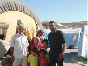 Dr. Saleem Al-Nuaimi stands with a family he worked with at a camp for internally displaced people in Syria.