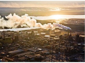 The setting sun reflects off a tailings pond behind Syncrude’s oilsands upgrading facility north of Fort McMurray in this June 18, 2013 file photo.
