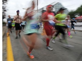 Runners burst out of the starting gate to begin the Half-Marathon portion of the Edmonton Marathon on Jasper Avenue in Edmonton on Sunday Aug. 24, 2014.