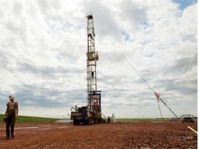 In this 2011 file photo, Austin Mitchell walks away from an oil derrick outside of Williston, N.D. A glut of oil supplies has helped depress world prices.