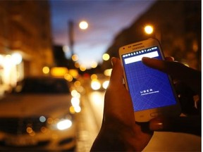 In this photo illustration, a woman uses the Uber app on an Samsung smartphone in Berlin, Germany. Edmonton should embrace the ride-sharing program, says Chris LaBossiere.