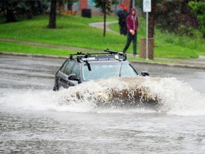 Vehicles drive through a flooded road at 102nd Street and 100th Avenue because of heavy rainfall in Edmonton, July 25, 2014.