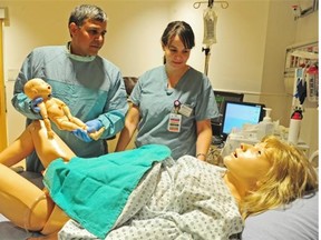 Dr. Venu Jain, left, and clinical nurse educator Erin Hayward deliver a simulated baby from the new simulated patient at the Simulation Centre at the Lois Hole Hospital for Women in Edmonton on Tuesday, Nov. 25, 2014. The new centre will allow doctors to practise what to do in critical situations. The mannequins, known as simulators can breathe, blink, have have lungs are are equipped with microphones and speakers.