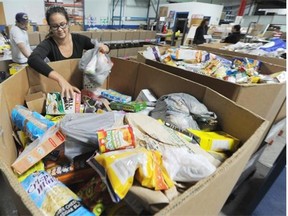 Volunteers Michaela Thamwong and Fred Papirnik, background, help sort donated food items at the Edmonton Food Bank on Wednesday Sept. 24, 2014.