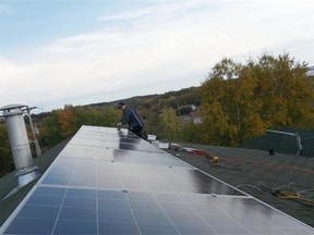 A worker installs solar panels on the roof of Athabasca Chipewyan First Nation’s elder and youth lodge.