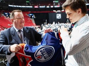 Anton Lander of the Edmonton Oilers puts on a team jersey handed to him from Stu MacGregor after being drafted in the second round of the 2009 NHL Entry Draft at the Bell Centre on June 27, 2009 in Montreal.