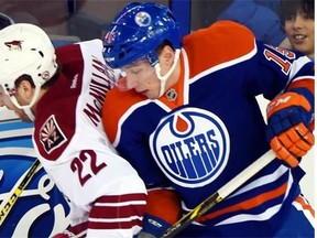 Arizona Coyotes forward Bran­don Mc­Millan, left, battles with Edmonton Oilers forward Tyler Pit­lick during NHL action at Rexall Place in Edmonton on Dec. 23, 2014.