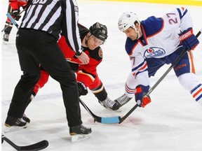 Boyd Gordon of the Edmonton Oilers takes a faceoff against Matt Stajan of the Calgary Flames in a National Hockey League game at Scotiabank Saddledome in Calgary on Dec. 27, 2014.