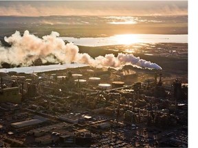 The setting sun reflects off a tailings pond behind Syncrude's oilsands upgrading facility north of Fort McMurray, Alta. on June 18, 2013. The plant converts bitumen which is extracted from oilsands into synthetic crude oil which is then piped to southern refineries.
