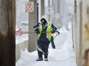 Dale Anderson of G & J Parking Lot Maintenance, shovels the sidewalk along Stadium Road in the falling snow in Edmonton on Friday Jan. 2, 2015.