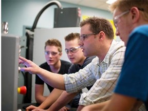 Darren Roth, teacher at Calmar Secondary School, helps program the new CNC machine just recently installed at the school as, from left, Jorn Peeters, Conley Wurban, and Tucker Weldon take notes.