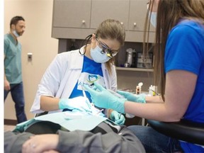 Dentist Julia Rutkowski, left, drills out a cavity.