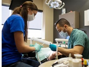 Dentist Yousif Chaaban, right, and Chantelle Auclair, office manager for Abbotsfield Dental, work together on a patient as the clinic teamed up with YESS (Youth Empowerment and Support Services) to give free dental work to young people.