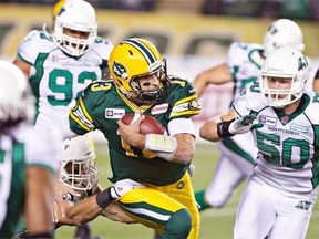 Edmonton Eskimos quarterback Mike Reilly tries to escape from a host of pursing Saskatchewan Roughriders — from left, Weldon Brown, Trevor Guyton and Chad Kilgore — during a Canadian Football League game at Commonwealth Stadium on Sept. 26, 2014.
