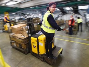 Electric pallet jack operator Brenda Fritsch moves parcels at Canada Post’s mail processing plant in Edmonton on Dec. 12, 2014.