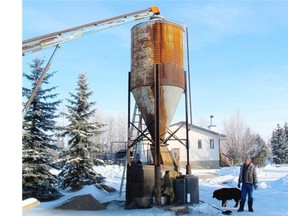 Harvey Schmidt and his dog George with the coal-fired furnace that heats the home and shop on Schmidt’s farm west of Calmar.