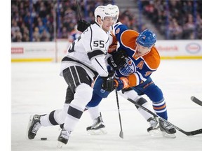 Jeff Schultz of the Los Angeles Kings and Taylor Hall (4) of the Edmonton Oilers battle for the puck during first-period action at Rexall in Edmonton on Dec. 30, 2014.
