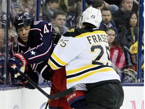 Matt Fraser of the Boston Bruins checks Columbus Blue Jackets’ Dalton Prout into the boards during a National Hockey League game at Columbus, Ohio, on Dec. 27, 2014.