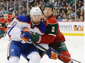 Minnesota Wild defenseman Keith Ballard (2) holds Edmonton Oilers left wing Luke Gazdic (20) off the puck during the second period of an NHL hockey game in St. Paul, Minn., Tuesday, March 11, 2014.