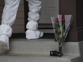 A forensic officer walks into the home past a bouquet of flowers and a pair of children's shoes on the front step. Edmonton police are investigating a home at 180th Avenue and 83rd Street where seven bodies were discovered.