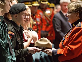 Matthew Wynn, son of slain RCMP Constable David Wynn is handed his dad's hat from Deputy Commissioner Marianne Ryan, during the funeral procession for Constable Wynn, in St. Albert, Alta., on Monday, January 26, 2015