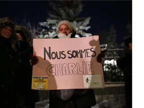 People hold signs and show their support at a vigil at the French Embassy in Ottawa, for the slain journalists of the Paris satirical magazine Charlie Hebdo who were murdered this morning at their offices in Paris.