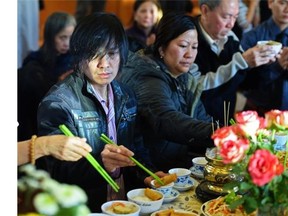 Tam Nguyen, left, who lost his wife and daughter, makes a food offering at the altar at the Truc Lam Monastery during a memorial service for the victims of last week's mass murder in Edmonton on Sunday Jan. 4, 2015.