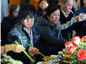 Tam Nguyen, left, lost his wife and daughter in last week’s mass murder in Edmonton. He makes a food offering at the altar at the Truc Lam Monastery during a memorial service for the victims on Jan. 4, 2015.