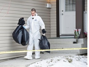 Police remove evidence from northside home at 180 Avenue and 83 Street where seven people were slain Monday night.